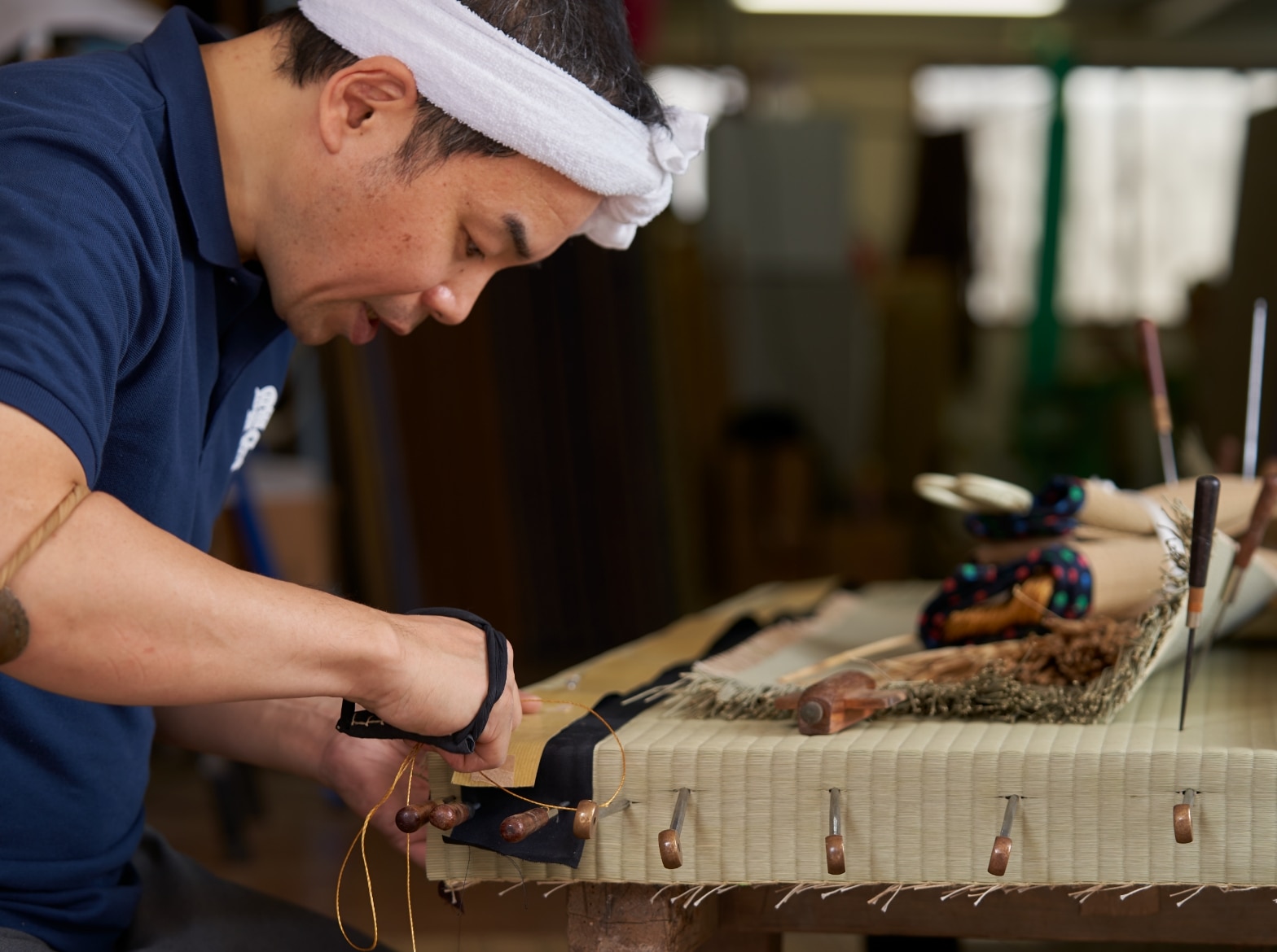 畳を縫っている金井功の真剣な横顔