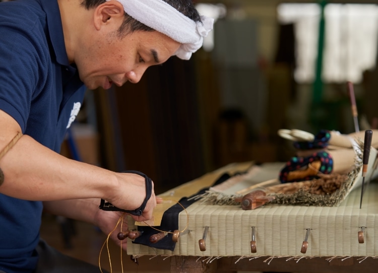 畳を縫っている金井功の真剣な横顔